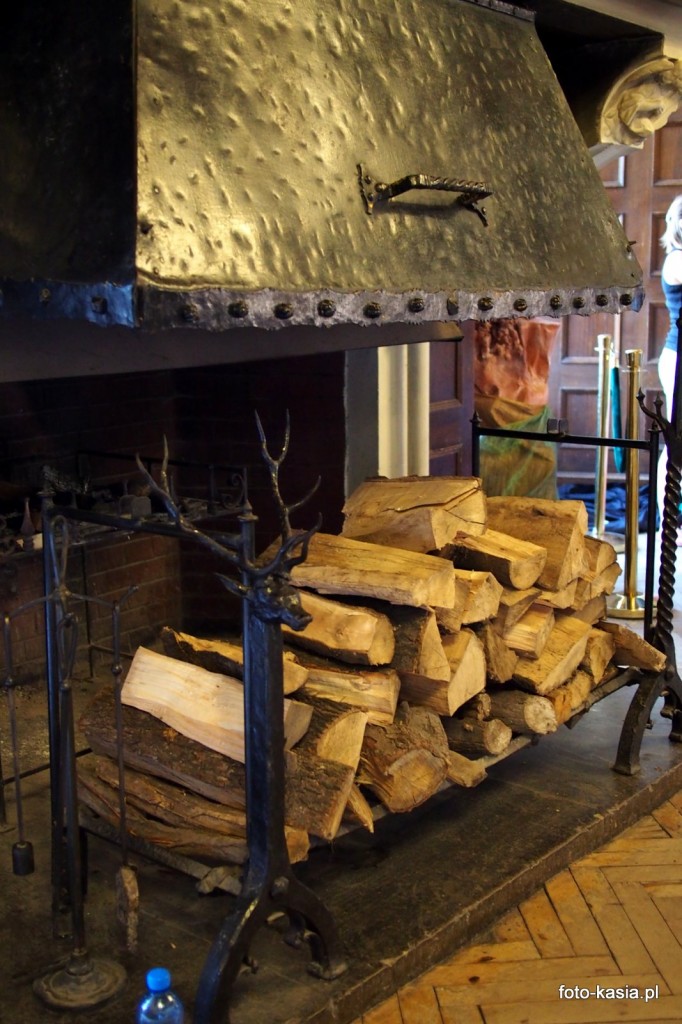 Kominek w sali rycerskiej pachnie świeżo palonym drewnem.